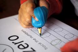 child writing "0" with a pencil, with a rubber pencil grip
